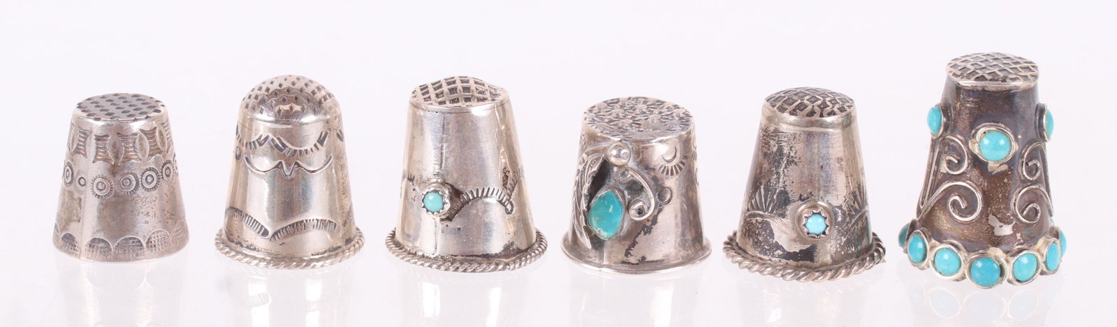 A Group of Silver Native American Thimbles: Six examples, all 20th century, some have either turquoise or enamel decoration. Dimensions: From 5/8" to 1" tall, the total approximate gross weight is 0.80 troy ounces. Provenance: From a local esta