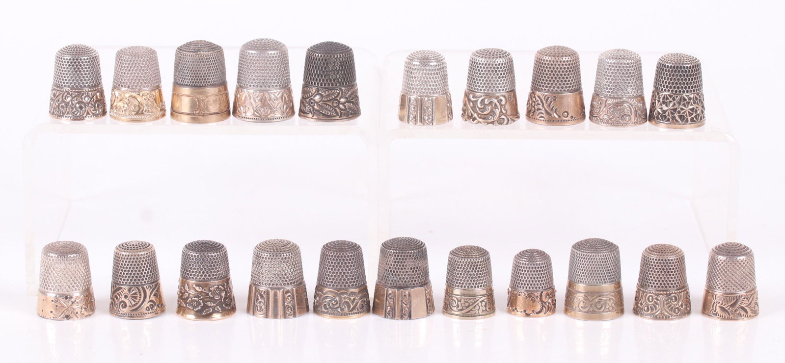 A Group of Sterling and Gold Thimbles: Twenty one examples, all with engraved or raised decoration. Late 19th or 20th century. Dimensions: Various sizes, the total expected weight is 3.9 troy ounces. Provenance: From a local estate.