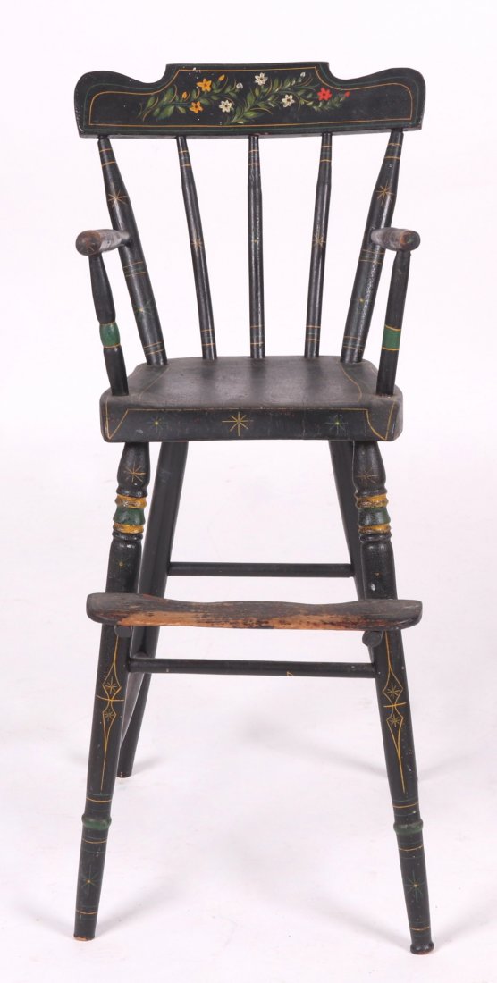 A Windsor High Chair: 19th century, with turned legs, foot rest, plank seat and a back with three spindles and crestrail. In old black paint with floral decoration. Dimensions:13 1/2" x 17", the height is 34".