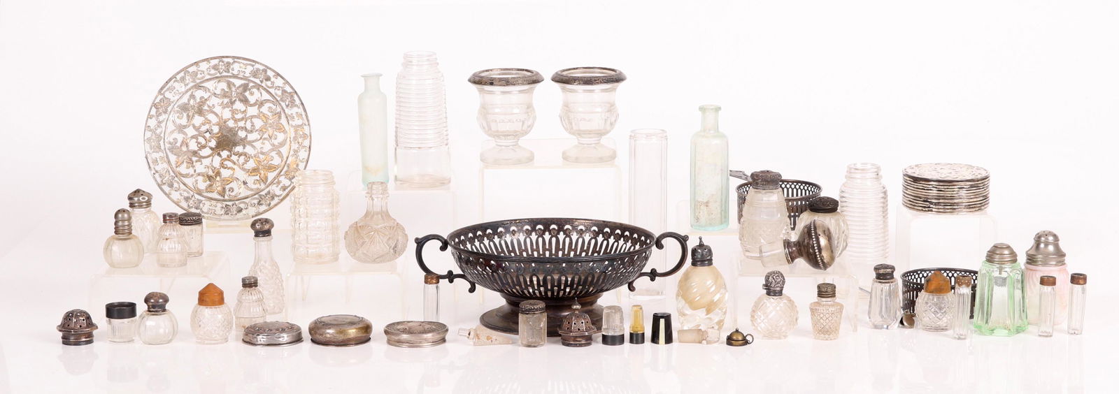 Estate Lot, Silver Tableware: Comprising: a set of twelve glass and sterling coasters, a larger matching wine bottle coaster, a pair of sterling ramekin holders, a reticulated sterling holder meant for a glass serving dish, and a