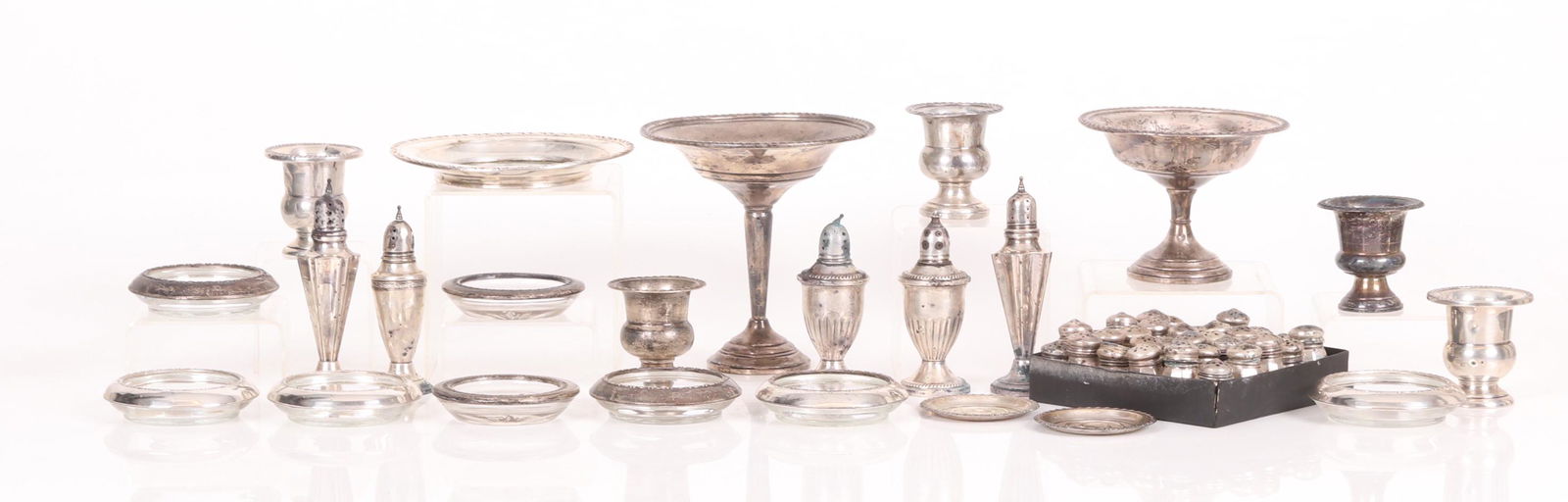 A Group of Sterling Silver Tableware: Comprising: a compote (weighted) by Preisner, 36 small shakers, a compote (weighted) marked P.S.CO, a glass and sterling wine bottle coaster by Amston, eight sterling and glass coasters, a pair of too