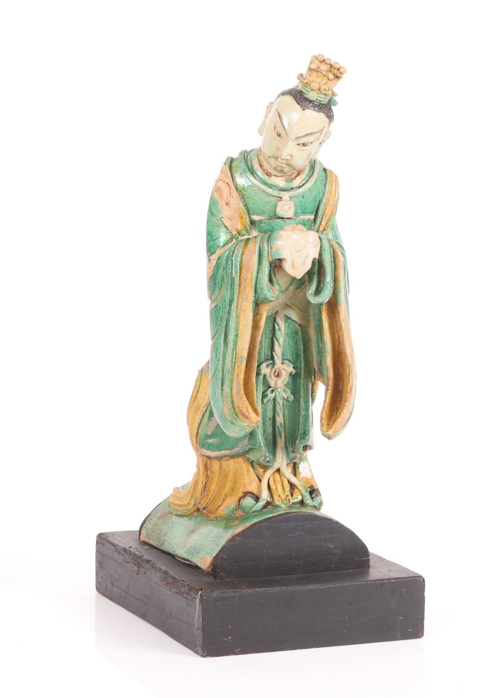 A Chinese Tang Dynasty Roof Tile: A large figural example with a yellow and green glaze. On a 20th century wooden stand. Dimensions: The stand is 7 1/2" x 9 1/2", the overall height is 18".