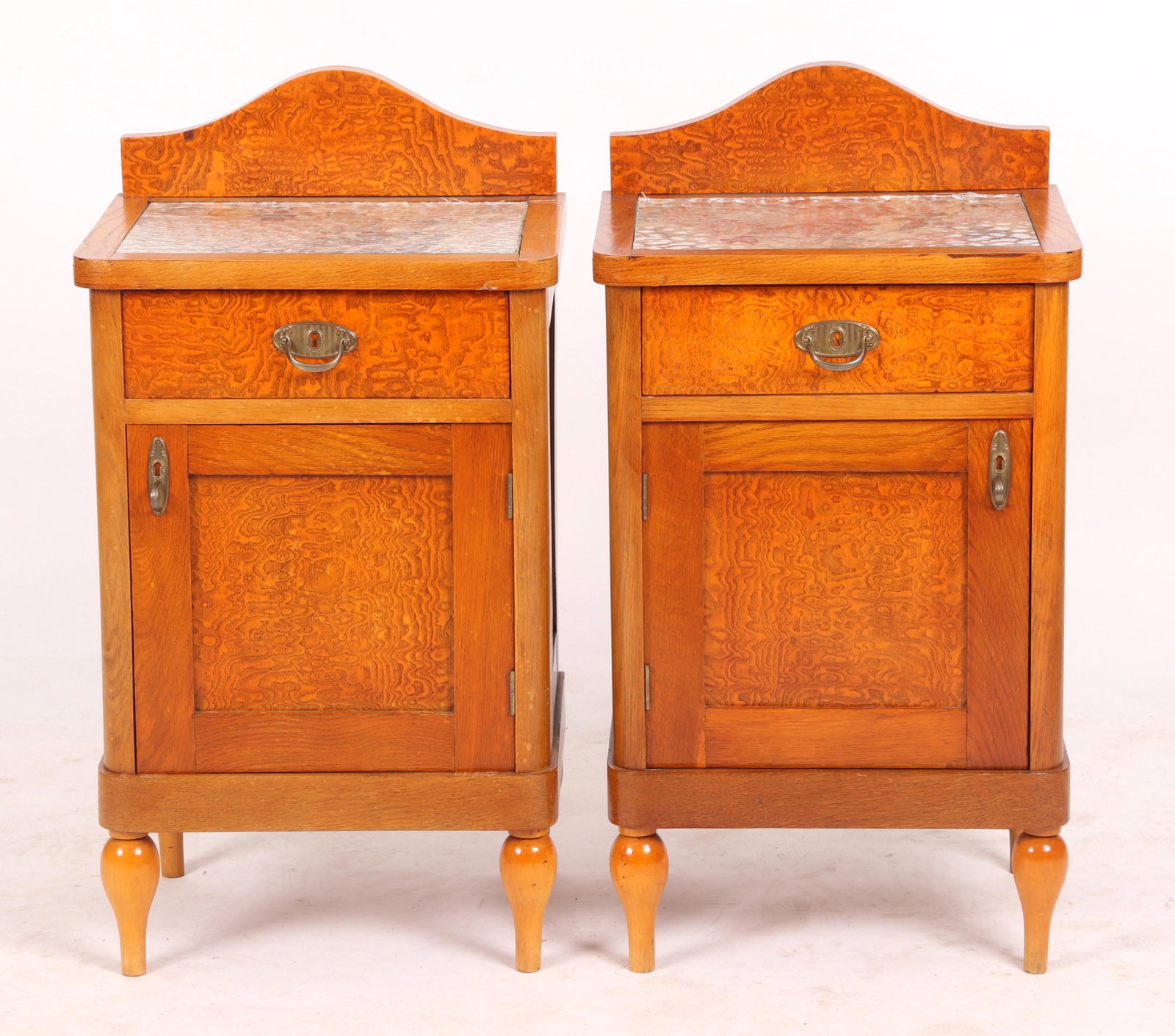 A Pair of Nightstands circa 1900: Each with turnip feet below a case with a single paneled door below a drawer, all below a top with replaced inset floral fabric and textured glass. Dimensions: Each is 18" x 14" and the overall height