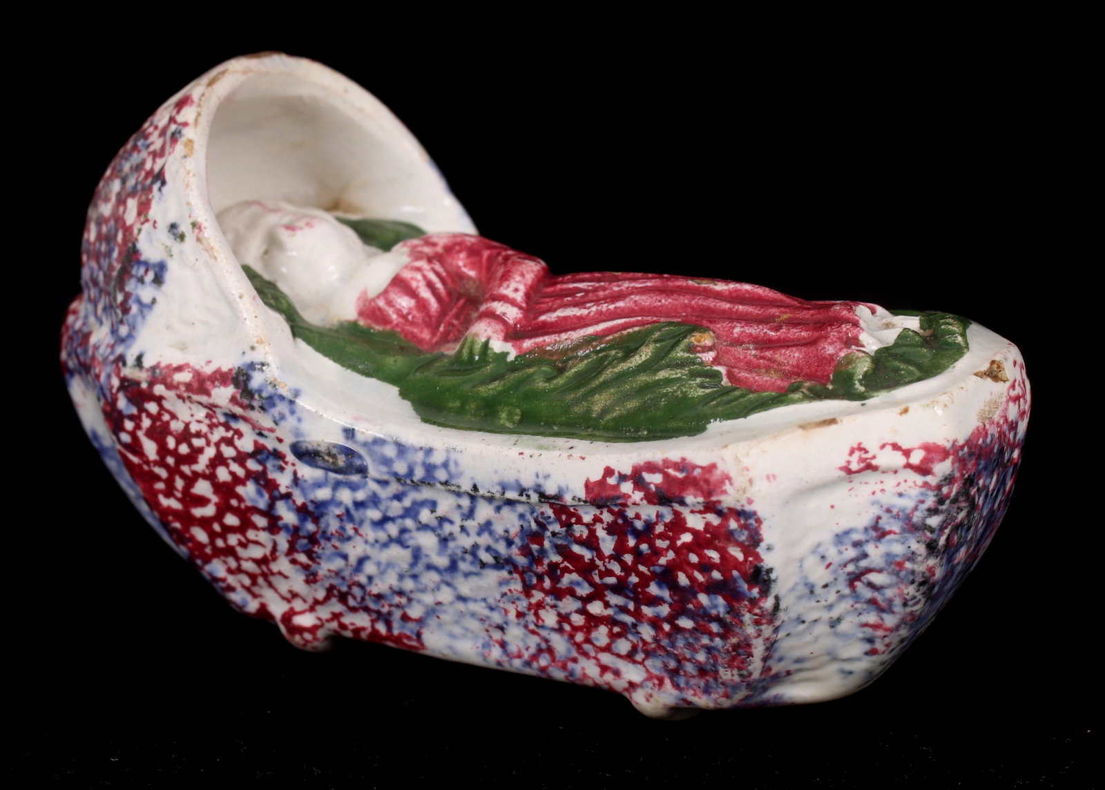 A Sponge Decorated English Staffordshire Cradle: Early 19th century, pearlware, with a sleeping child at the interior. Dimensions: 4" x 1 1/2" x 2". Provenance: From a Philadelphia estate.