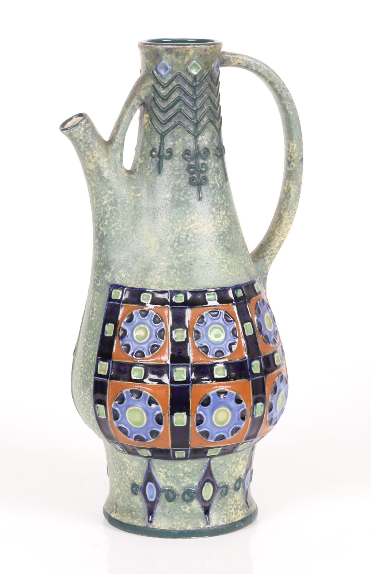 A Czech Amphora Pottery Ewer: Early 20th century, with a green glaze and repeated floral decoration, marked as pictured. Dimensions: 7 1/2" x 7", the height is 14 1/2".
