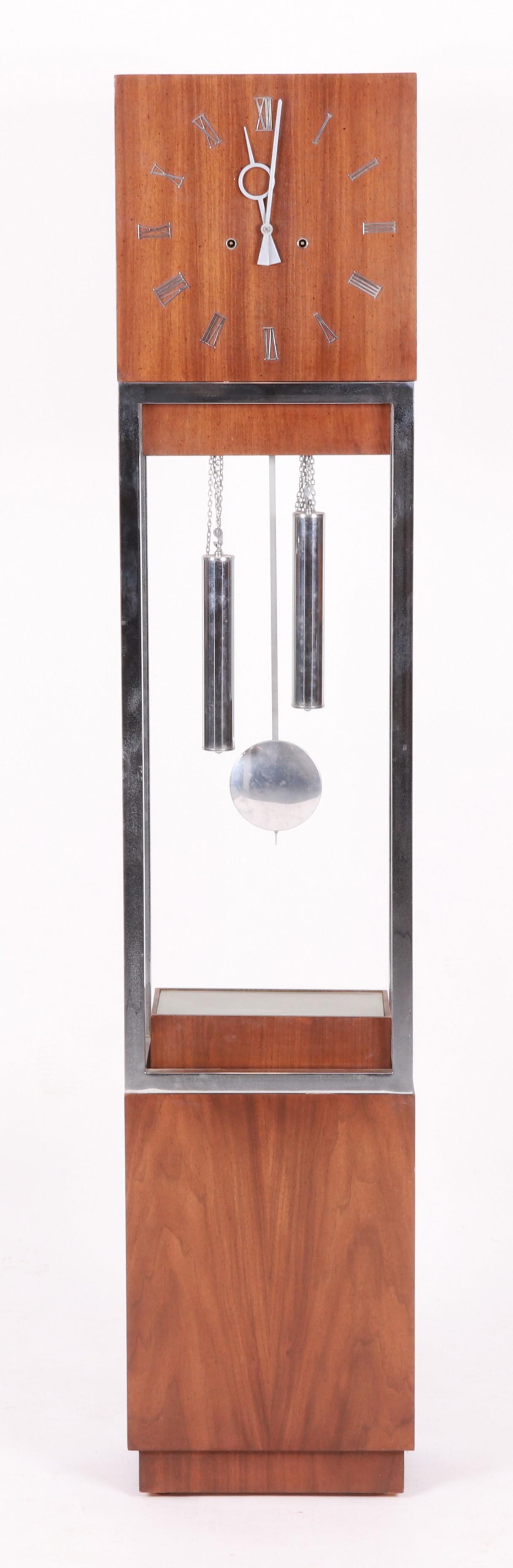 A Walnut and Chrome Mid Century Tall Case Clock: Circa 1960, with a German brass movement and low electric light. Dimensions:14" x 19", the height is 68". Provenance:From a NJ collection.