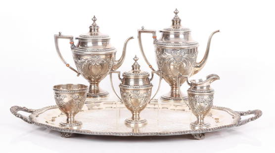 A Sterling Silver Tea Service: By Ellmore, a neoclassical set with hand chased decoration. There is a coffee pot, teapot, waste bowl, covered sugar and creamer. The set included an associated silver plated tray. Dimensions:From