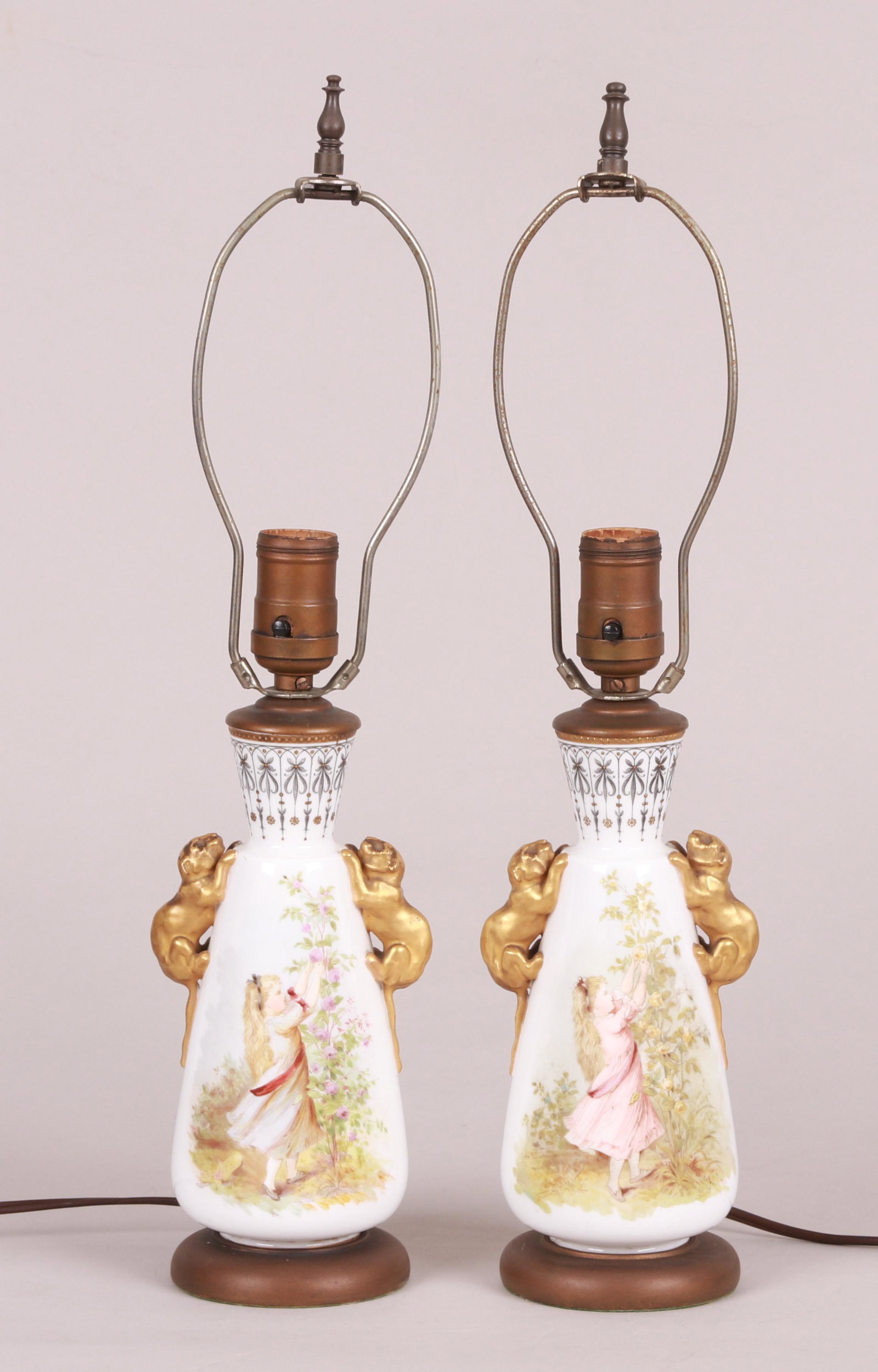 A Pair of Unusual Porcelain Victorian Lamps: Late 19th century, each with transfer and hand painted decoration and unusual gilt panther handles. These were vases that were later mounted as lamps. Dimensions:Each body is 4" in diameter and 8" tal