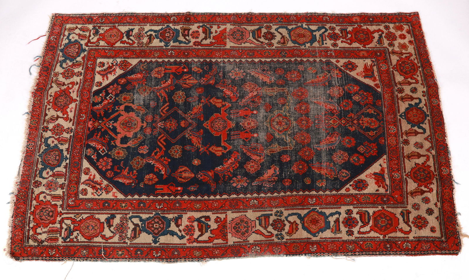 An Antique Persian Village Rug: Early 20th century, with a midnight blue field with red floral devices. Dimensions:83" x 54". Provenance:
