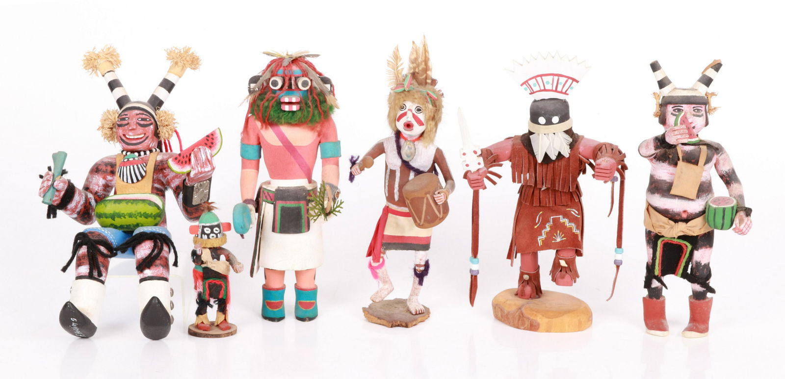 Six Kachinas: To include a seated figure holding a watermelon signed F. Healing, a standing figure holding a watermelon, an unsigned figure beating a drum, an unsigned figure holding a bow and pine needles, a small