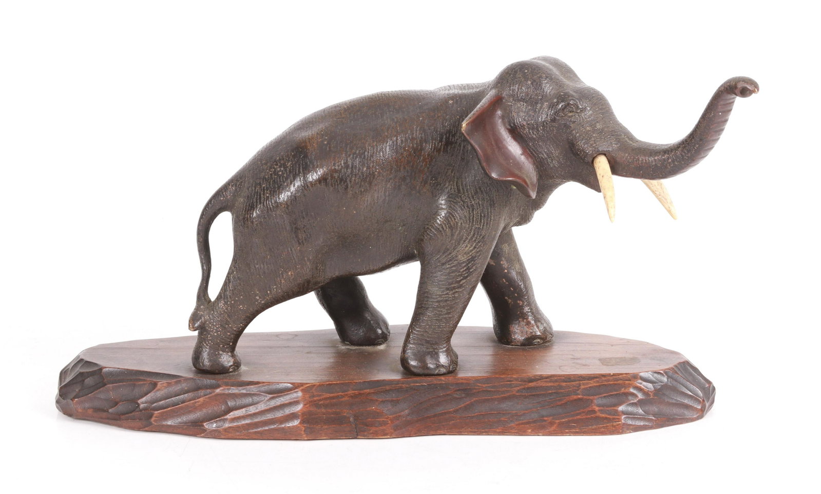 A Japanese Bronze Figure of an Elephant: Early 20th century, patinated bronze with bone tusks and a chip carved wooden base. Dimensions:The base is 13" x 5", the height is 7". Provenance: