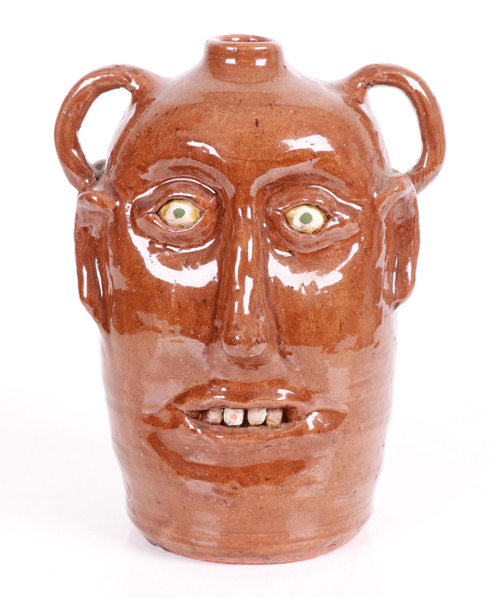 Reggie Meaders (1916 - 2009) Double Face Jug: Redware, with a brown glaze and painted eyes and teeth, signed as pictured. Dimensions: About 9" x 9", the height is 11". Provenance: From a Bucks County estate.