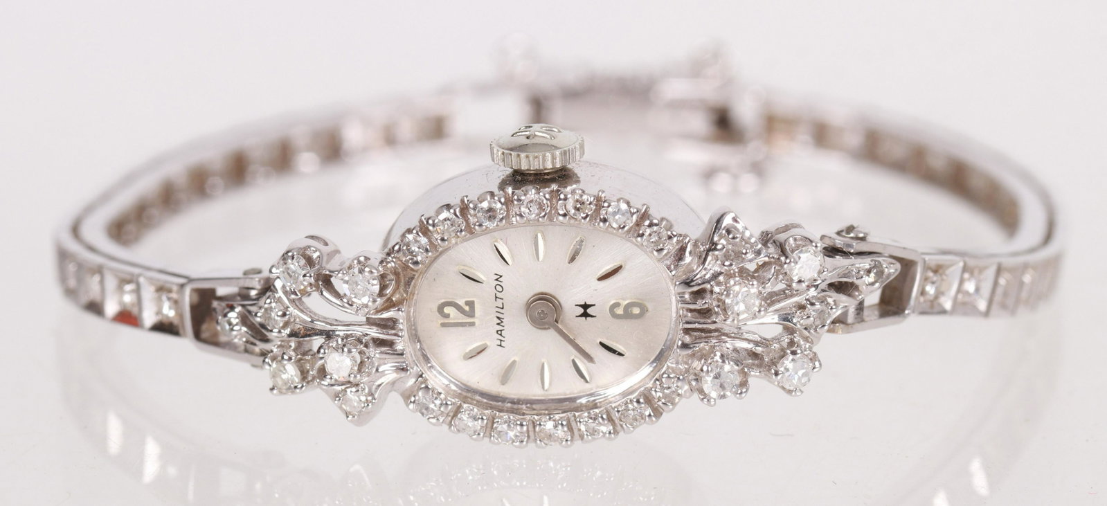 Ladies Hamilton Gold and Diamond Watch: A vintage example with a diamond encrusted case and diamonds all along the gold band. 14k white gold with 59 single cut diamonds. Dimensions:6 7/8" long, the case is 14mm. The total approximate gross 
