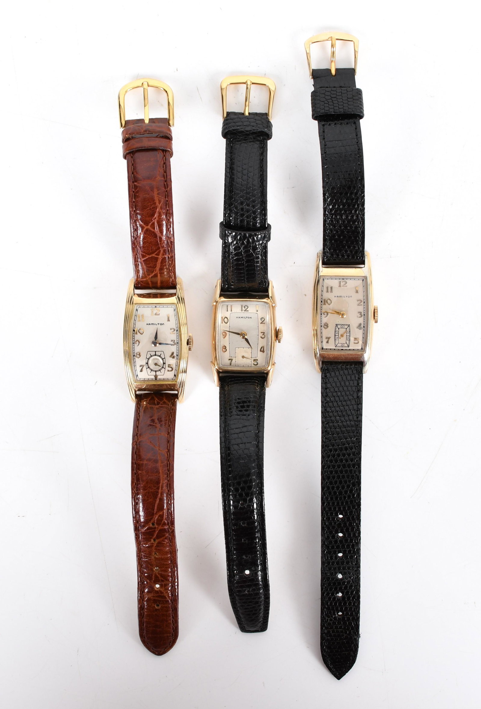 Three Hamilton Watches, Two Curved Examples: The two longer cased are in 14k gold filled curved cases and the other is in a 10k gold filled case with fancy lugs. Dimensions:The smaller is 25mm x 20mm x 9mm, the other two are 32mm x 21mm x 9mm th