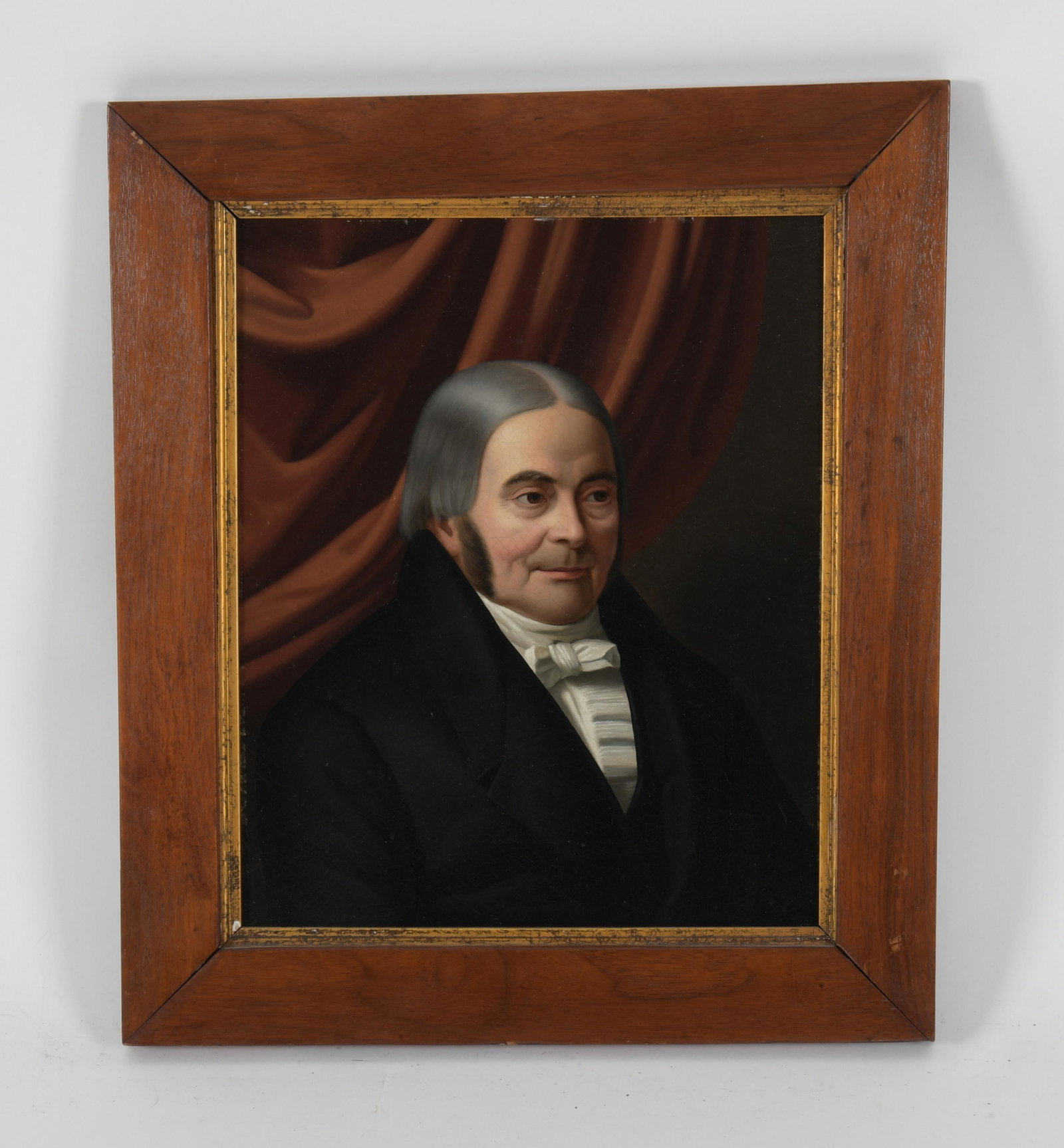 A Early 19th Century Portrait of a Gentleman: Oil on canvas, depicting an older gentleman posed before a red curtain, unsigned. Dimensions:14 1/2" x 12", the frame 19" x 16".