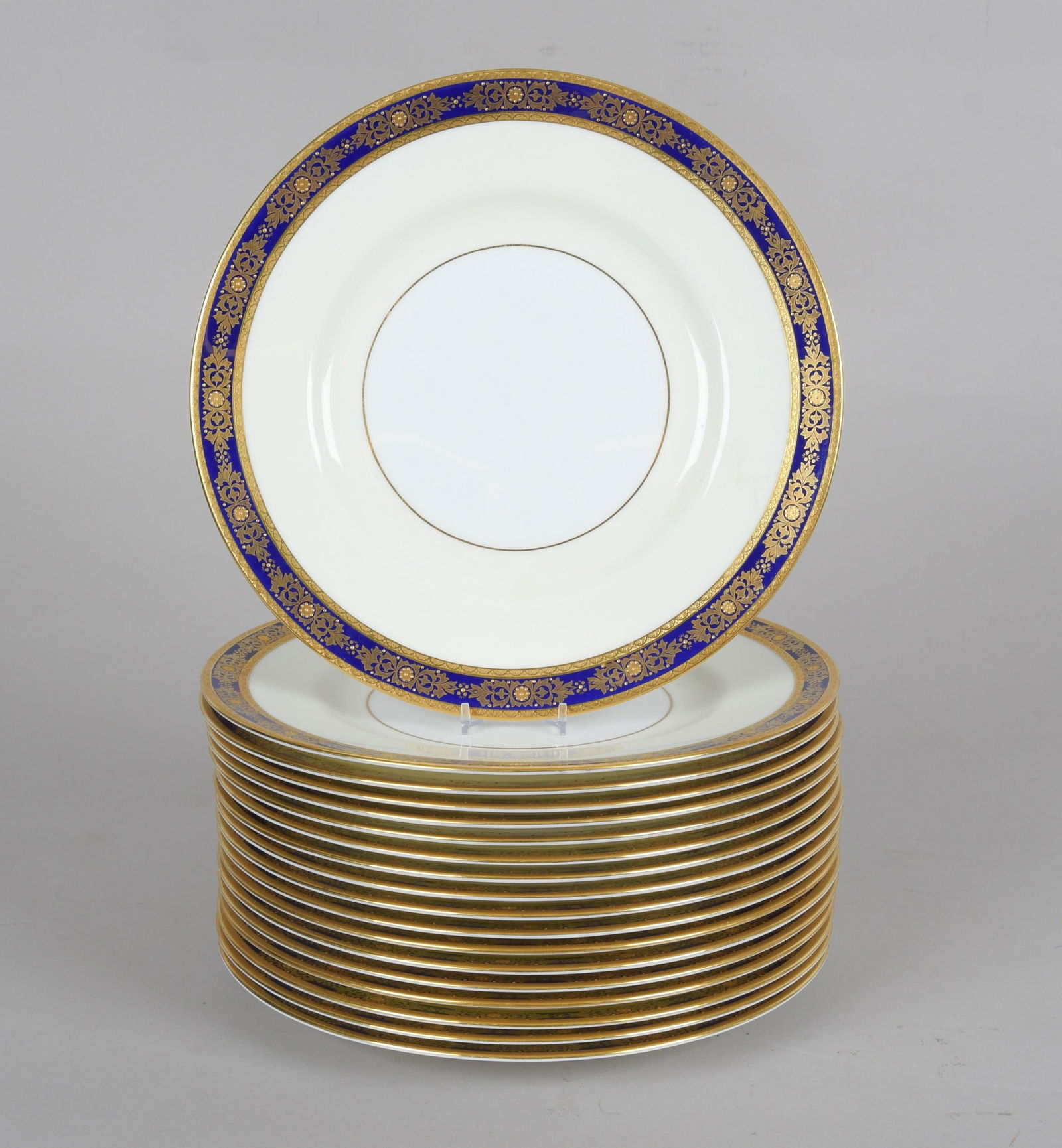 A Set of Eighteen Dinner Plates, Minton: 20th century, each with a gilt cobalt border that features raised elements. Marked as pictured. Dimension:Each is 10 5/8" in diameter.