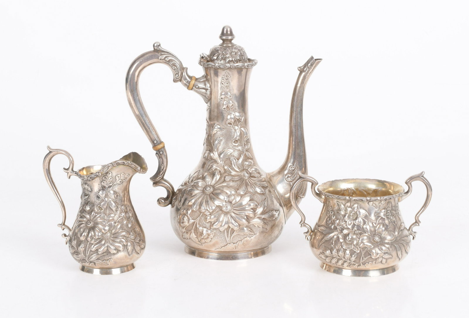 A Sterling Tea Set By Hamilton and Davis: An Art Nouveau period set with floral repousse decoration, each marked as pictured. Dimensions: From 4" x 2 1/2" to 7" x 5", the coffee pot is 9" tall. The total approximate weight is 28 troy ounces. 