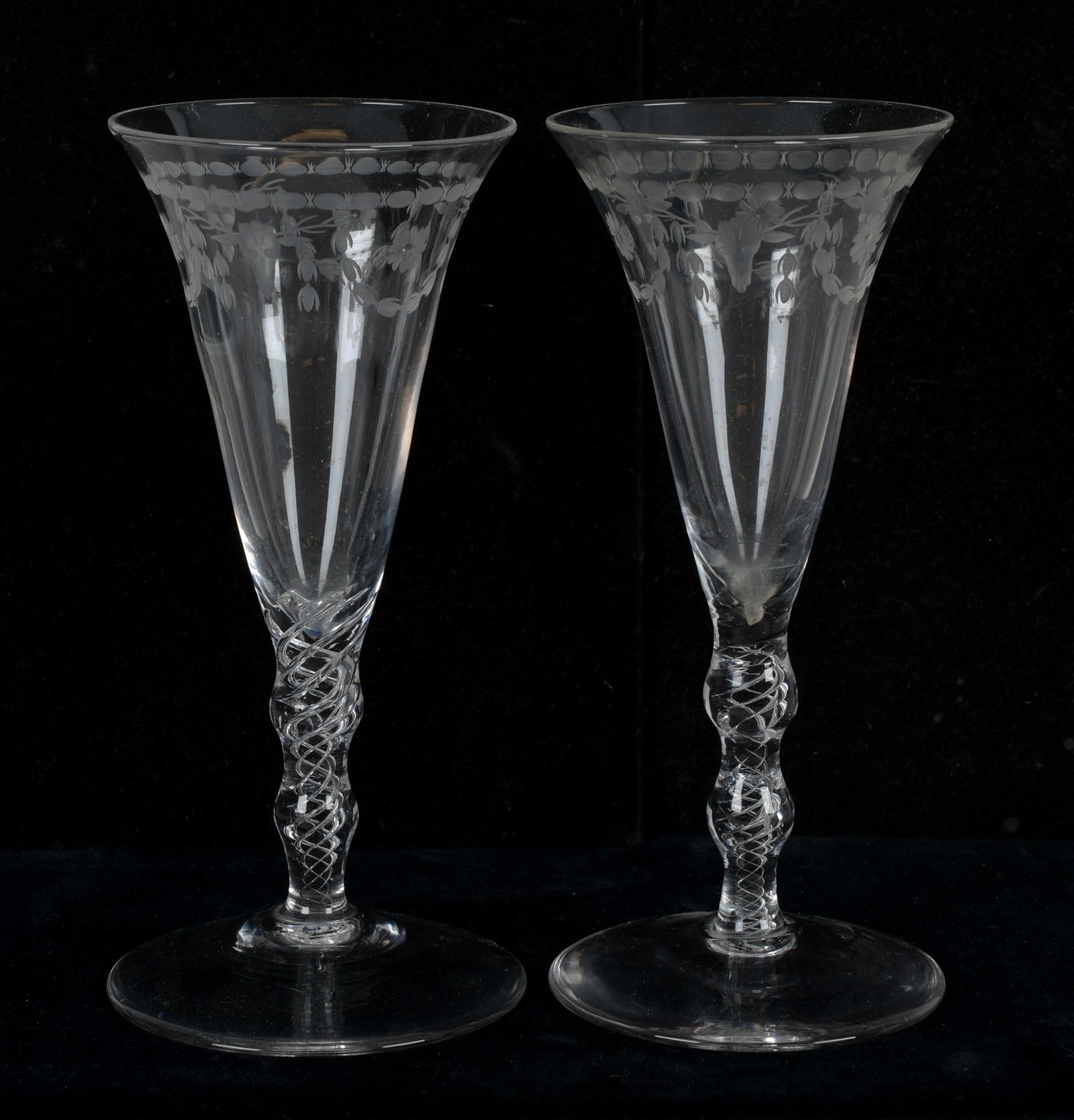 A Pair of Air Twist Wine Glasses: Early 19th century, the circular foot below an undulating and air twist decorated stem below an inverted bell form bowl, each etched with alternating stag heads and foliate slags. Dimensi