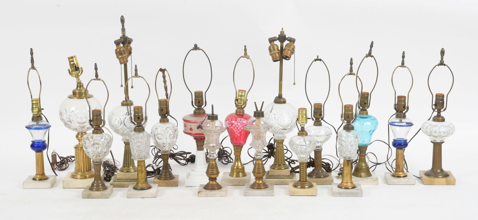 A Large Group of American Fluid Stand Lamps: All mid to late 19th century, various patterns, some colored. Dimensions: from 10 1/2" to 16" tall excluding the harps. 
