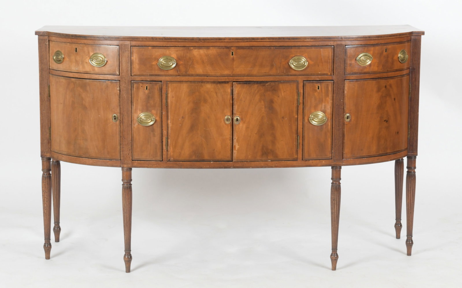 Federal Mahogany Inlaid Sideboard, Early 19th Century: A Federal Mahogany Inlaid Sideboard, Probably New England, Early 19th Century. The rectangular top having a bowed and broken front over a conforming case with three drawers below over a pair of c