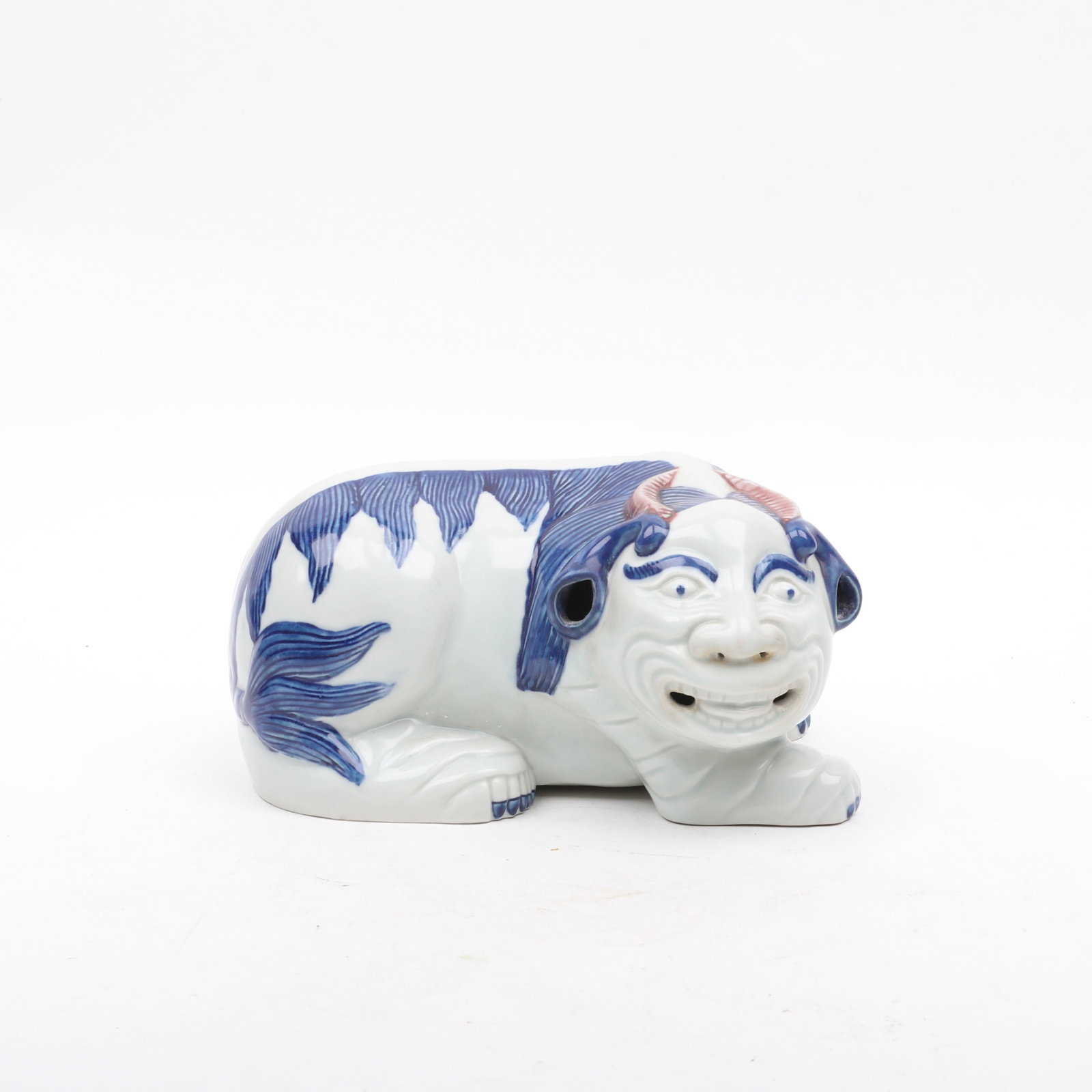 A Chinese Foo Lion Form Porcelain Pillow: A Chinese Foo Lion Form Porcelain Pillow A blue, white and iron red decorated example with human features, Qianlong mark but later Qing Dynasty. Dimensions: 9in x 7in, the height