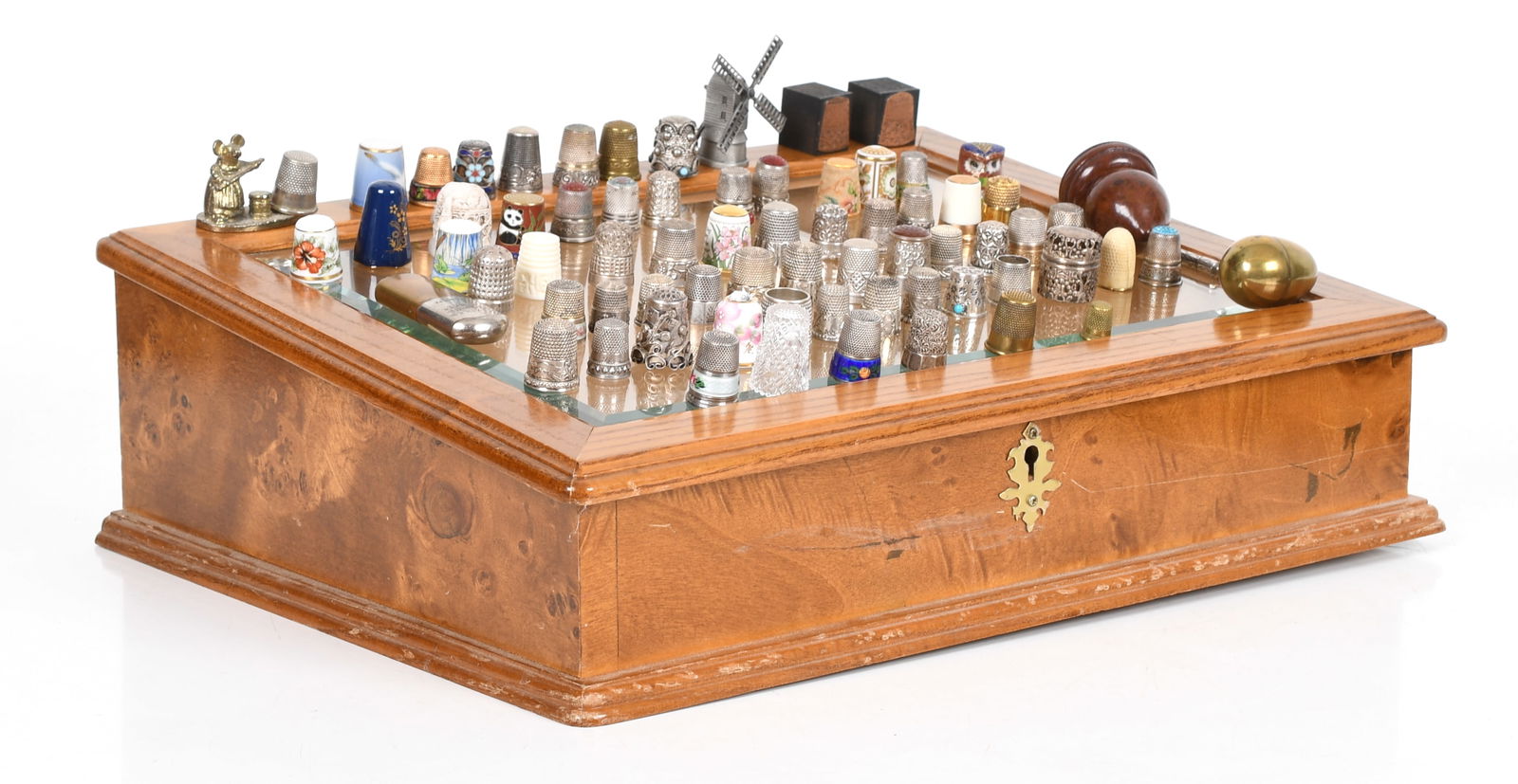 A Large Thimble Collection: A Large Thimble Collection Sixty five thimbles, a sterling spool case, two thimble ink stamps, two needle cases and a thimblescope. The lot also includes a wooden and glass presentation case. Th