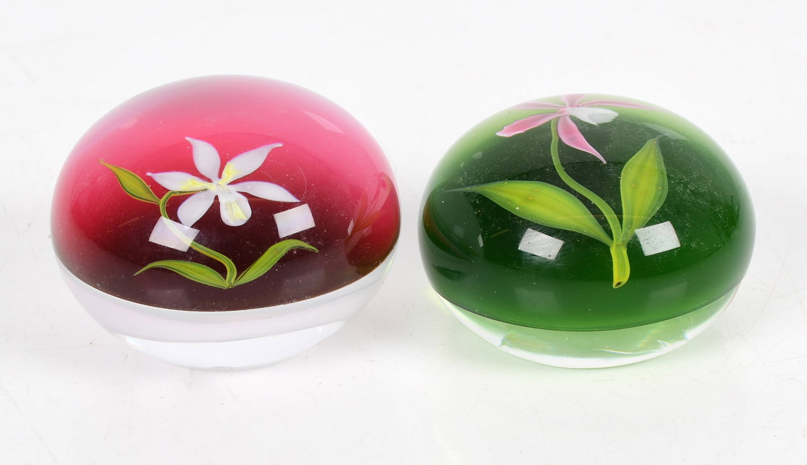 Two Paperweights by Paul Stankard (b. 1943): Two paperweights of orchids by Paul Stankard, one over a green ground, the other over a red-pink ground, both over a white base and interior "PS" both with etched signature and da