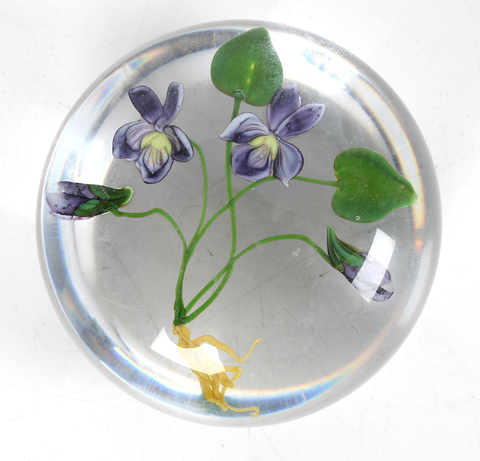 Paul Stankard (b. 1943) Paperweight, Violets: A droplet form botanical paperweight featuring violets by Paul Stankard, with interior "S" cane, marked "B677 1982". Dimensions: approximately H 1 7/8" x W 3 1/8"&nb