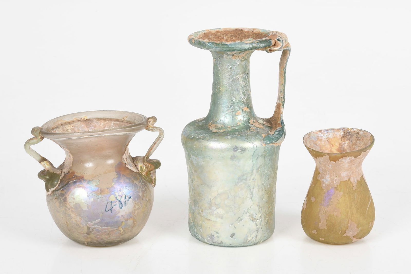 Three Pieces of Ancient Roman Glass: Three Pieces of Ancient Roman Glass A small jar with applied handles, a ewer with single handle and a small vessel without handles. Dimensions: from 2inn to 3in diameter, the heights range