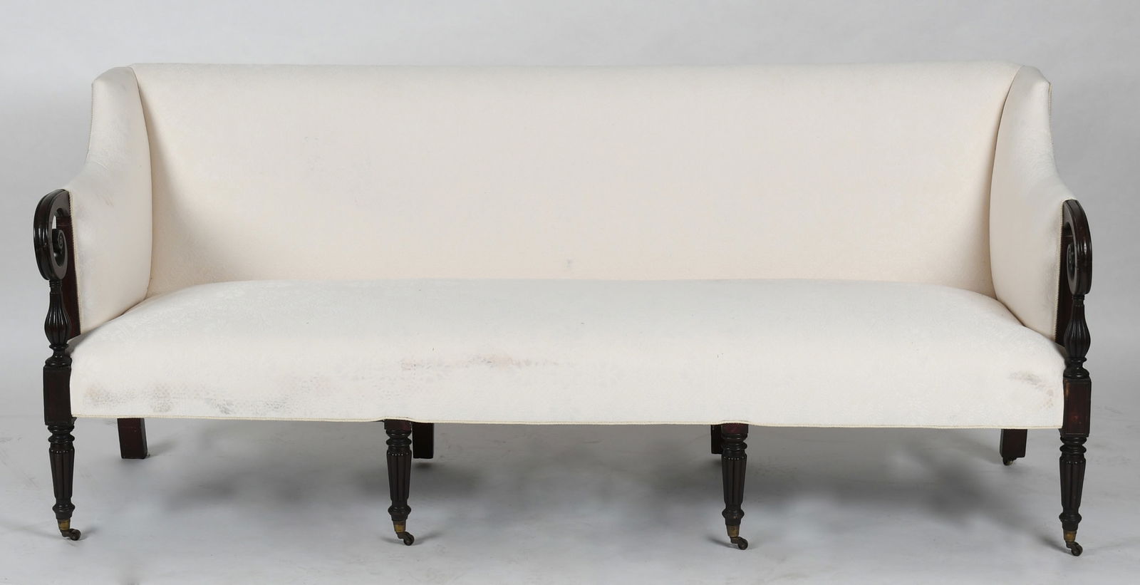 Federal Carved Mahogany Sofa, First Quarter 19th Century: A Federal Carved Mahogany Sofa, First Quarter 19th Century The rectangular back with down swept arms ending with scrolled volutes, and reeded supports, raised on reeded tapered legs, ending&