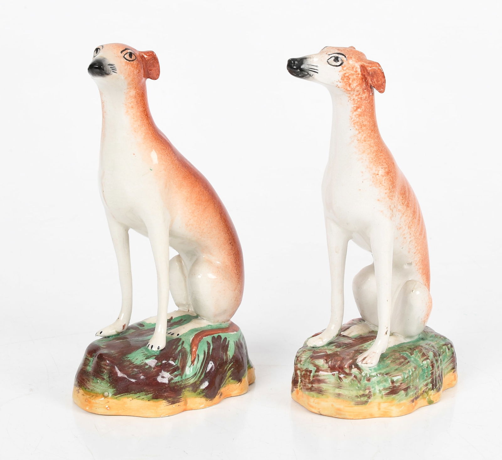 A Pair of English Staffordshire Seated Whippets, c. 1850: A Pair of English Staffordshire Seated Whippets, c. 1850 Modeled with turned heads, on naturalistic-painted bases. Dimensions: 3 in. x 4 3/8 in., 8 in. high Provenance: From a Bucks