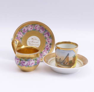 Zwei Freundschaftstassen mit Untertassen â€” Wien, 19.: Two Cups with Saucers / â€” Vienna, 19th century / A bulbous cup with a surrounding garland of roses on a gold background, in a saucer additionally the motto ''Wandle auf Rosen und