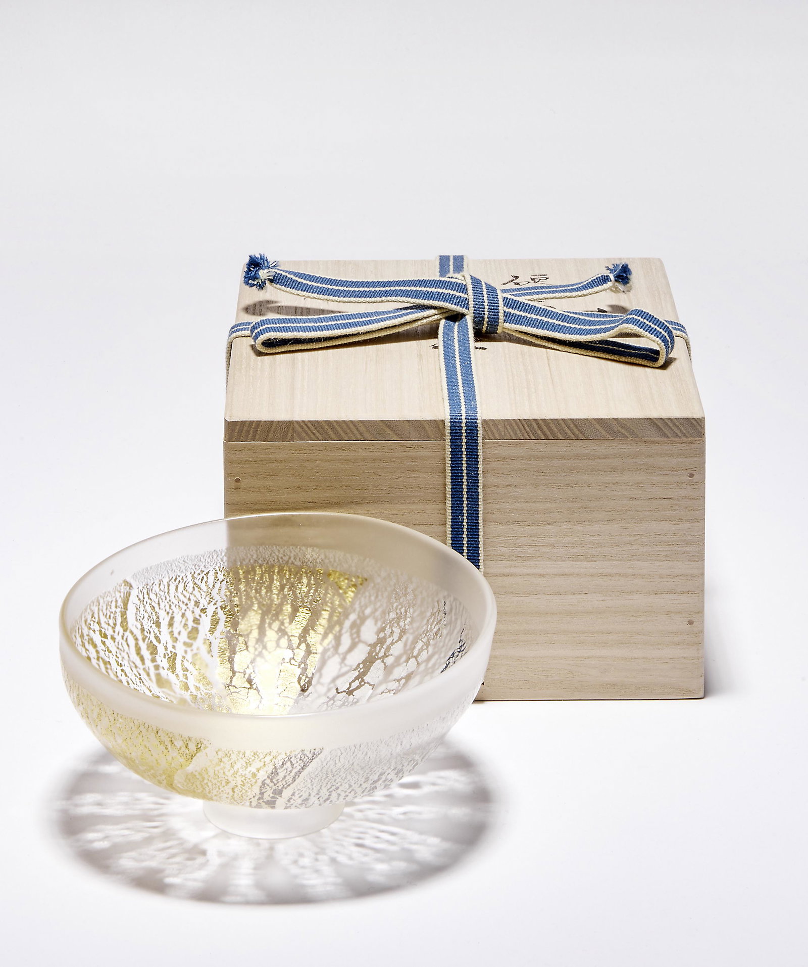 Fujita, Kyohei: Teeschale ''Tenmoku'' in originaler Holzschatulle: Fujita, Kyohei - Tea bowl ''Tenmoku'' in original wooden box (Tokyo 1921-2004 Chiba) Nearly hemispherical form over a round stand ring. Colourless, frosted glass with fused, cracked platinum and gold 