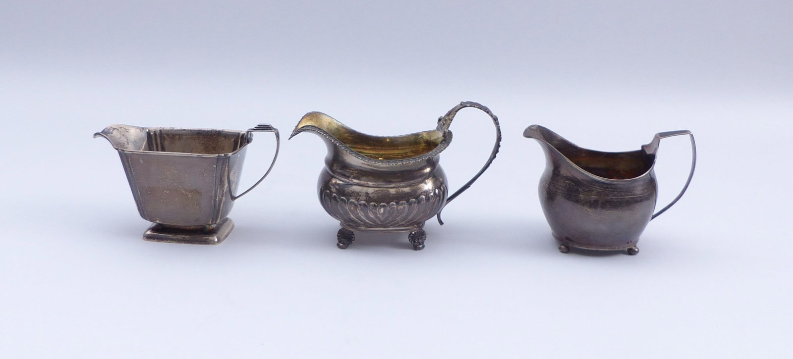 Drei Sahnegiesser, England, 19. und 20. Jh.: Three cream jugs . England, 19th and 20th C. Birmingham, Selfridge & Co Ltd, 1935. London, 1809 (?). London, Thomas Johnson, 1817. Silver. All with hallmarks and master's marks. H. 9 - 10.5 cm; total