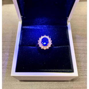 Lady Diana Blue Sapphire Yellow Gold Cluster Ring: A Lady Diana Blue Sapphire 14kt Yellow Gold Plated Cluster Ring. The Ring Displays a Cluster Of Simulated Diamonds Around A Oval Cut Blue Sapphire. The Ring Is Crafted With Precision & An Excellent