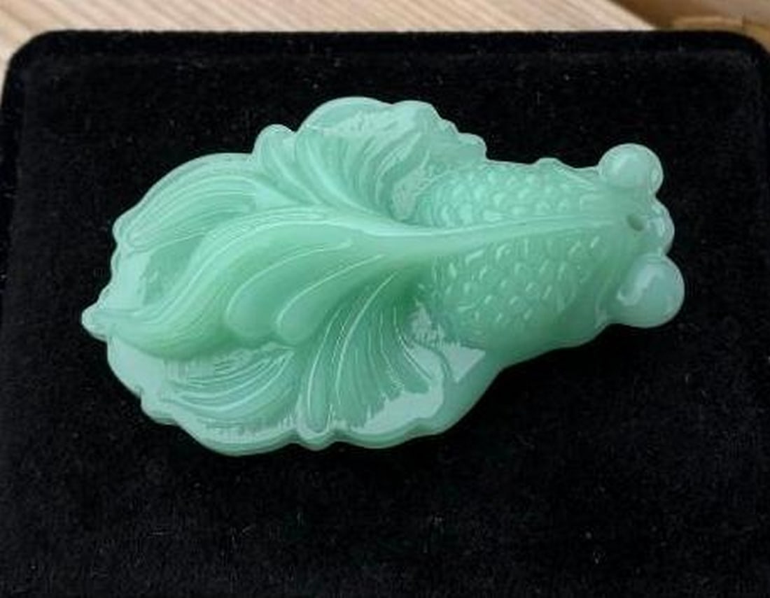 Hand-Carved Jade Fish Pendant: Hand-Carved Jade Fish Pendant This beautifully hand-carved jade pendant features a detailed fish design, long revered as a symbol of abundance, harmony, and good luck. Crafted from jade and polished