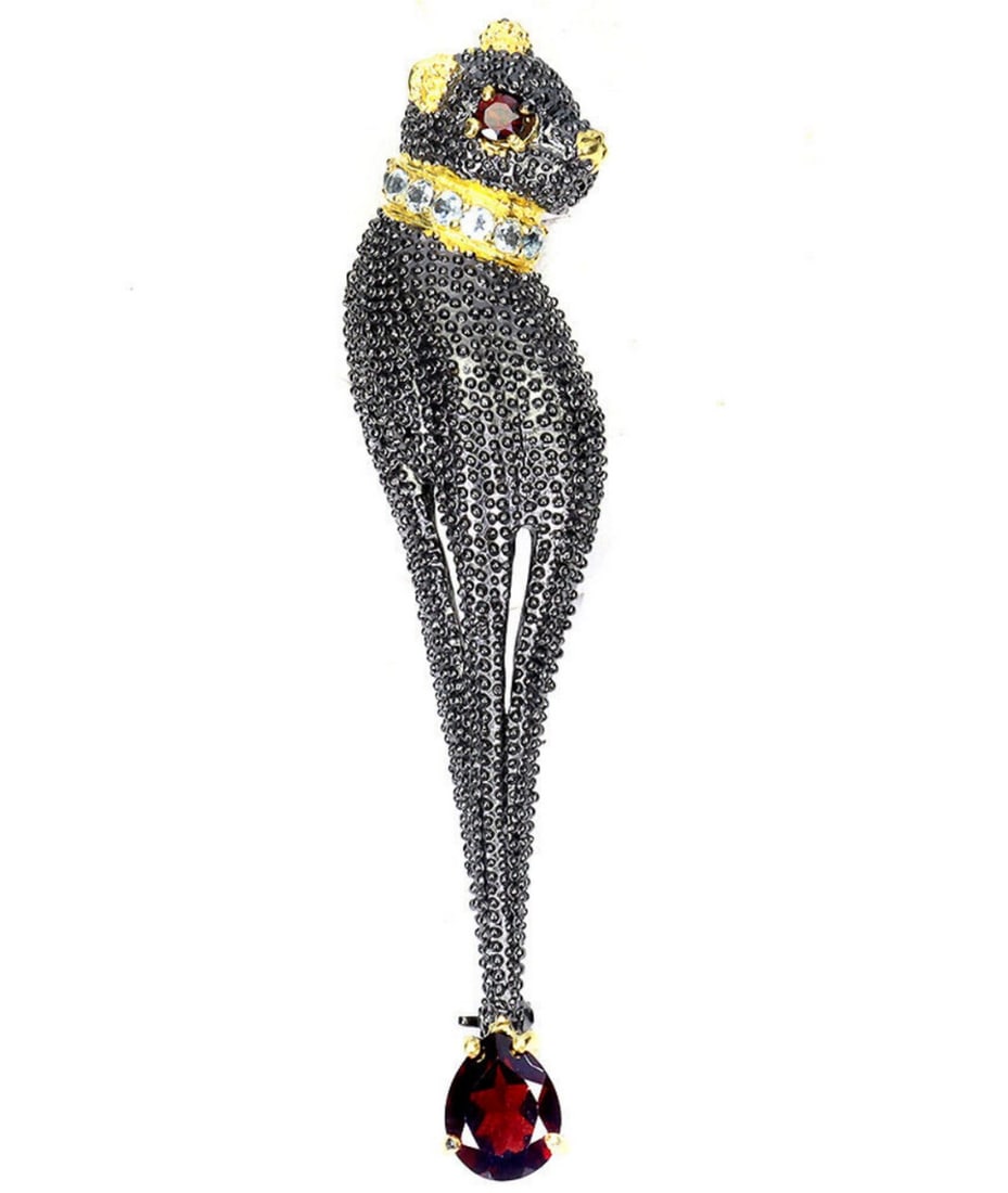 Rouge Mozambique Garnet and Blue Topaz Jewelled Tiger Brooch: Rouge Mozambique Garnet and Blue Topaz Jewelled Tiger Brooch This brooch is an eyecatcher. It features red mozambique as the cats eye and dangling off the tail. Its coller is studded with pale blue t