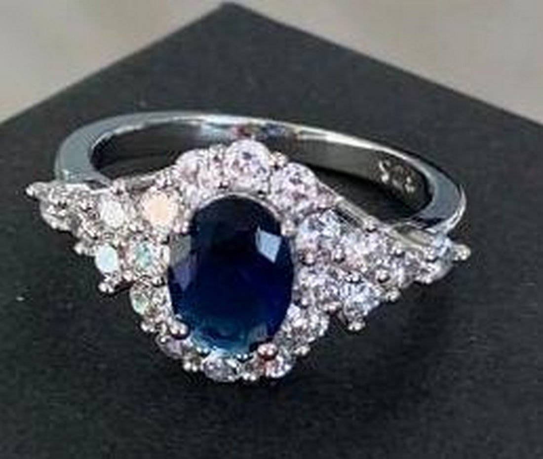 Sterling Silver Ring with Blue Center Stone & Crystal Halo: Sterling Silver Ring with Blue Center Stone & Crystal Halo A striking blend of elegance and sparkle. This sterling silver ring features a brilliant blue stone at its center, encircled by a