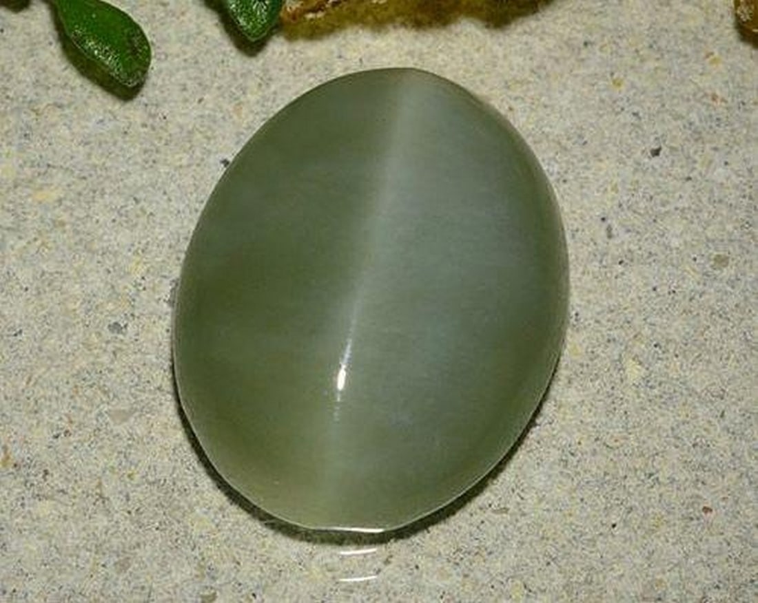 6.48 ct Natural Medium Green Actinolite Cat's Eye, Oval Cabochon, Translucent, United States: 6.48 ct Natural Medium Green Actinolite Cat's Eye, Oval Cabochon, Translucent, United States Natural Actinolite Cat’s Eye gemstone weighing 6.48 carats, cut in an oval cabochon with a medium gre