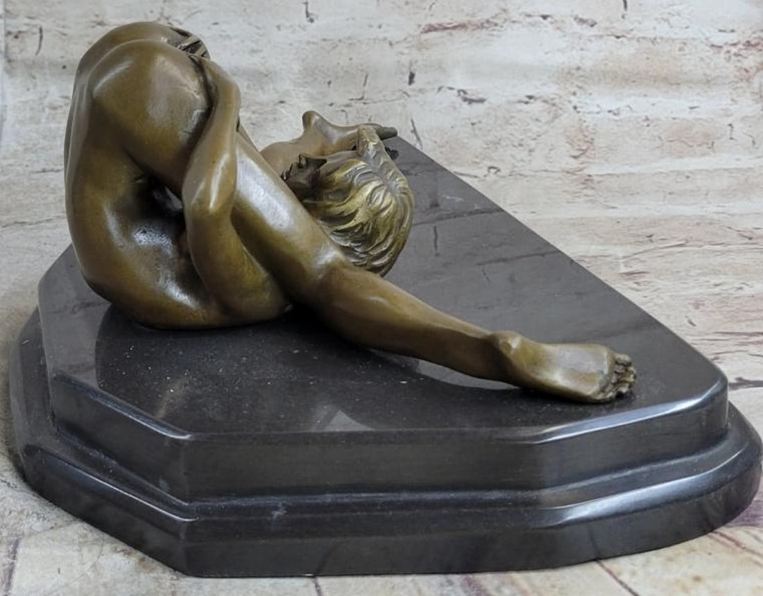 Serenity in Surrender Bronze Sculpture: Serenity in Surrender Bronze Sculpture This exquisite bronze sculpture, bearing the signature of renowned artist Nino Oliviero, depicts a nude woman lying down, holding her legs to her chest in a po
