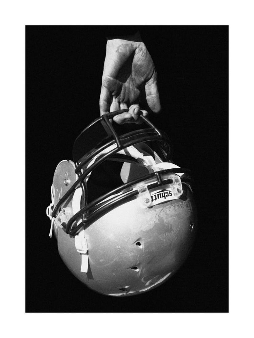 Helmet Grip Poster: Helmet Grip Poster A black and white poster featuring a close-up of a hand grasping an American football helmet. The grainy photographic texture adds depth and a vintage feel, making it ideal for