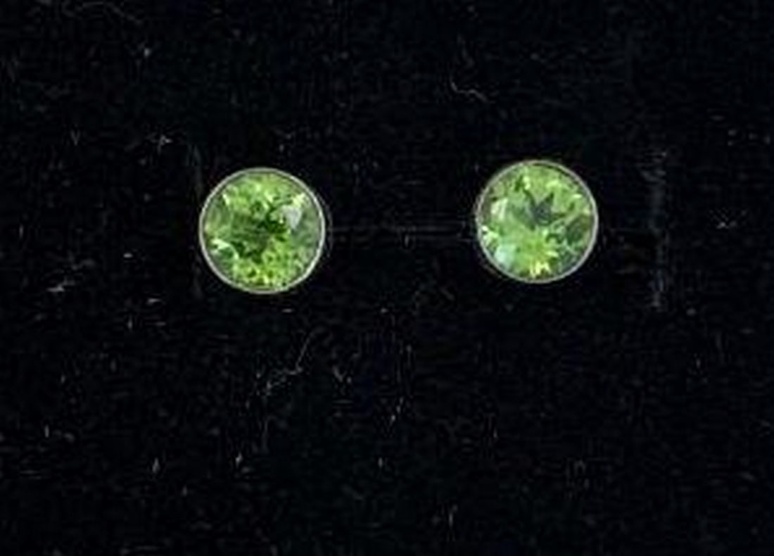 Peridot Stud Earrings with Faceted Cut: Peridot Stud Earrings with Faceted Cut This radiant pair of stud earrings features round, faceted peridot gemstones that shimmer with a vibrant green hue. Expertly cut to enhance their natural brillia