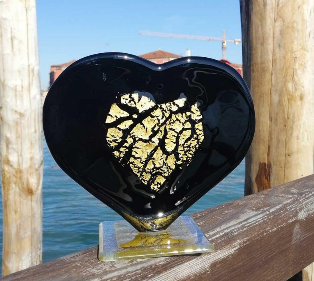 Black Murano Heart with 24k Gold: Black Murano Heart with 24k Gold Handcrafted using the fused glass technique, this exclusive heart-shaped artwork features a smaller heart adorned with real gold. The base is made of crystal glass