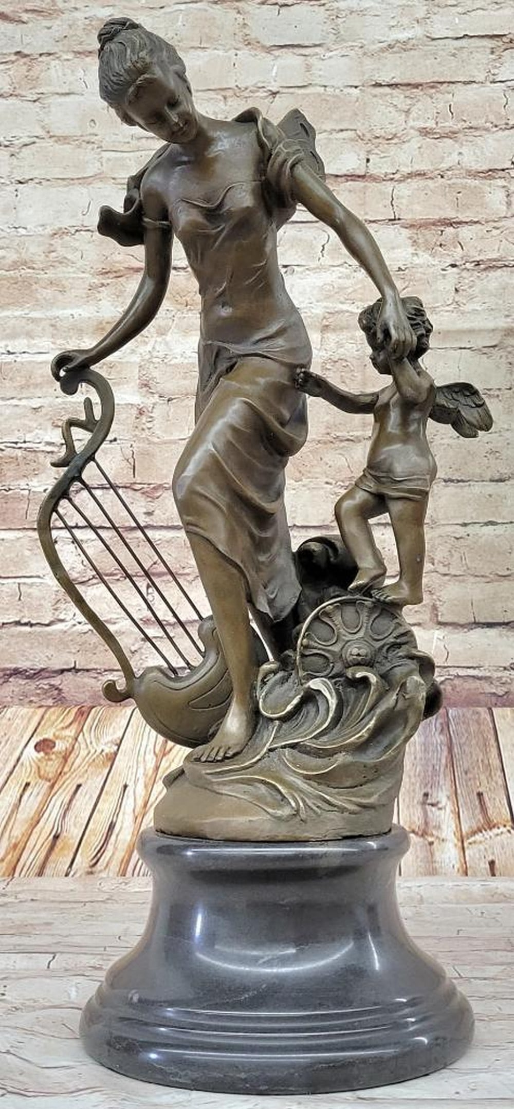 Cherub Along Side Adult Musician Angel Sculpture - 25lbs: A young cherub reaches to a fairy to gain her attention. The beautiful fairy reaches back to the cherub with a delicate to his playful curls. She's holding a musical Harps in this enchanting sculp