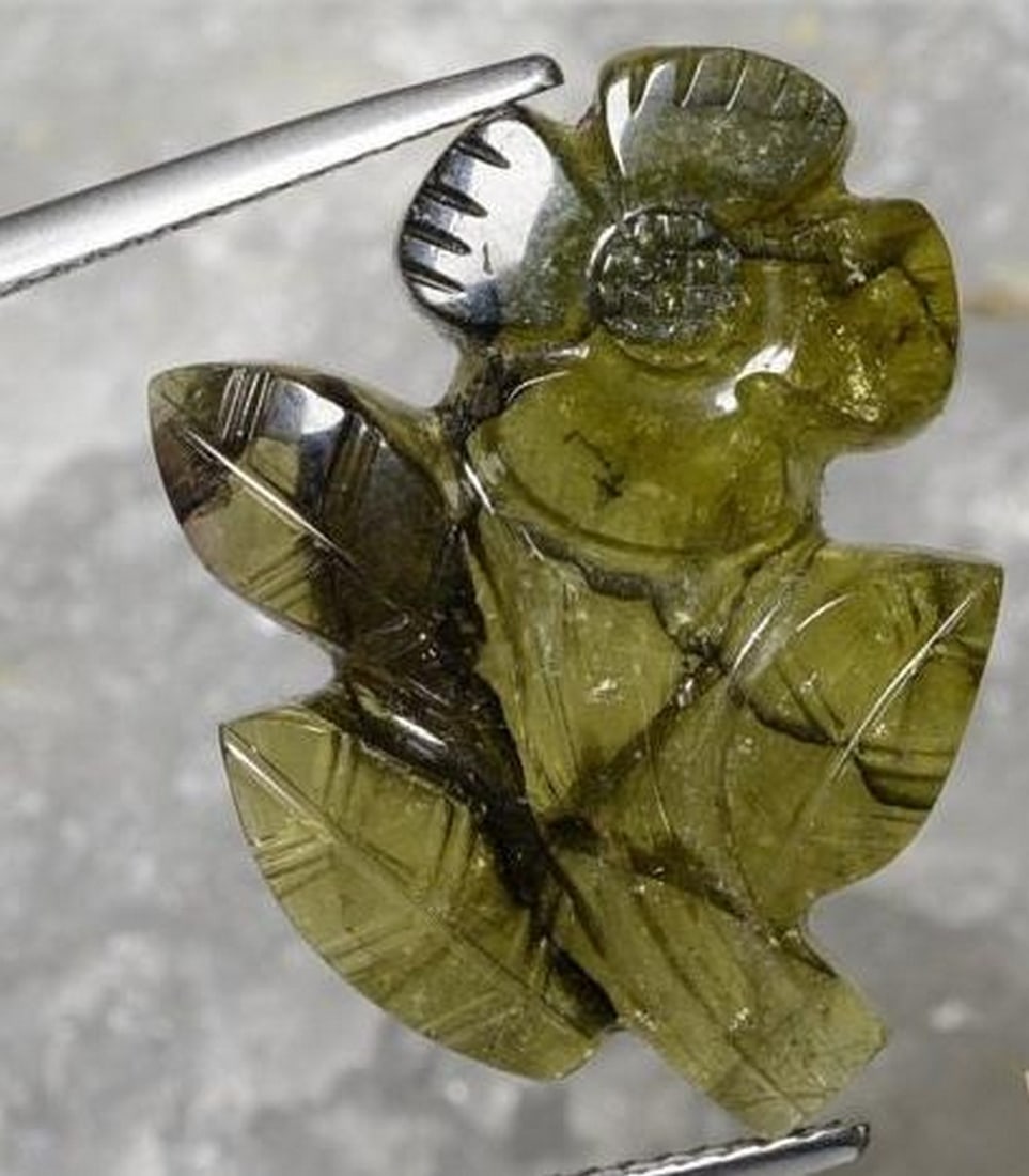 Warm Green Tourmaline Carved Full Flower Gemstone: Warm Green Tourmaline Carved Full Flower Gemstone Expertly carved from warm green tourmaline, this unique loose gemstone depicts a complete flower (petals, stem, and leaves) all sculpted in intricate