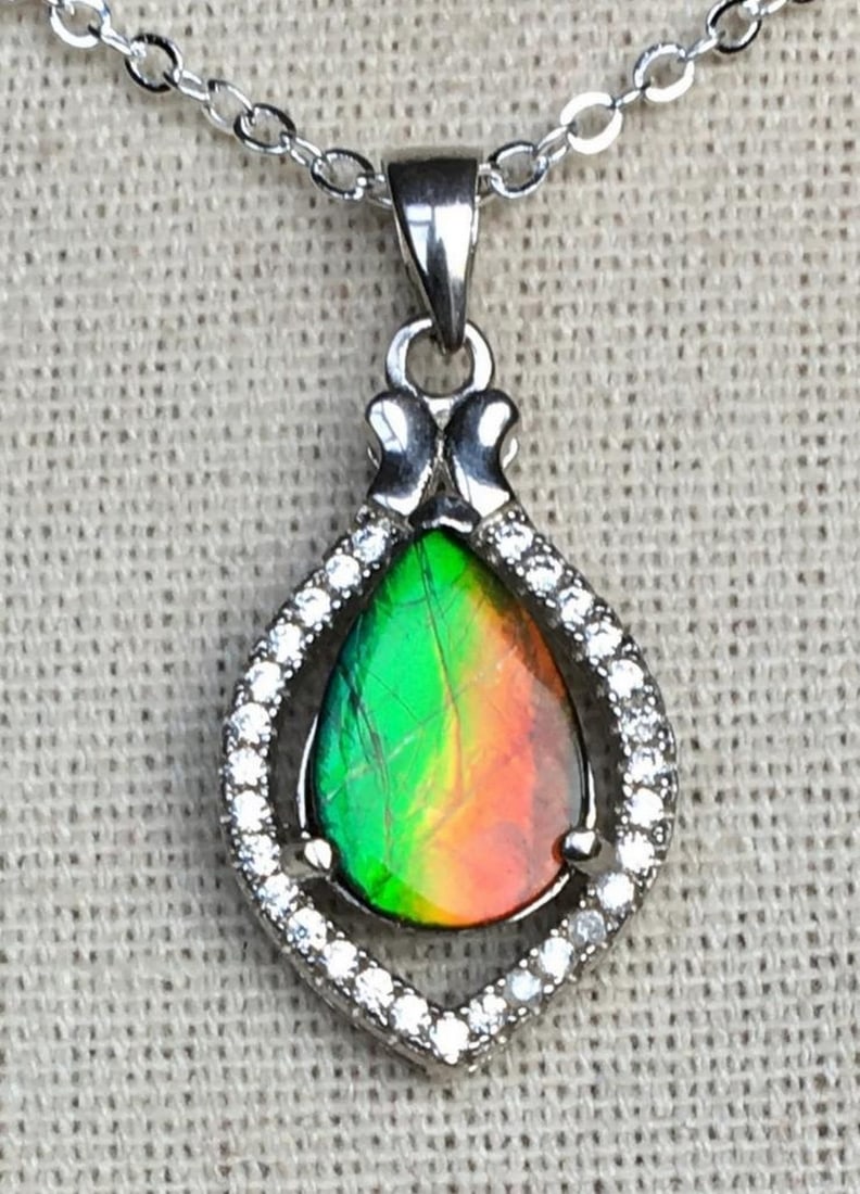 Teardrop Ammolite Pendant with CZ Accents: Teardrop Ammolite Pendant with CZ Accents This ammolite pendant features a 12mm x 8mm quartz-capped triplet, set in sterling silver with CZ accents. The gem is vibrant and appears even more striking