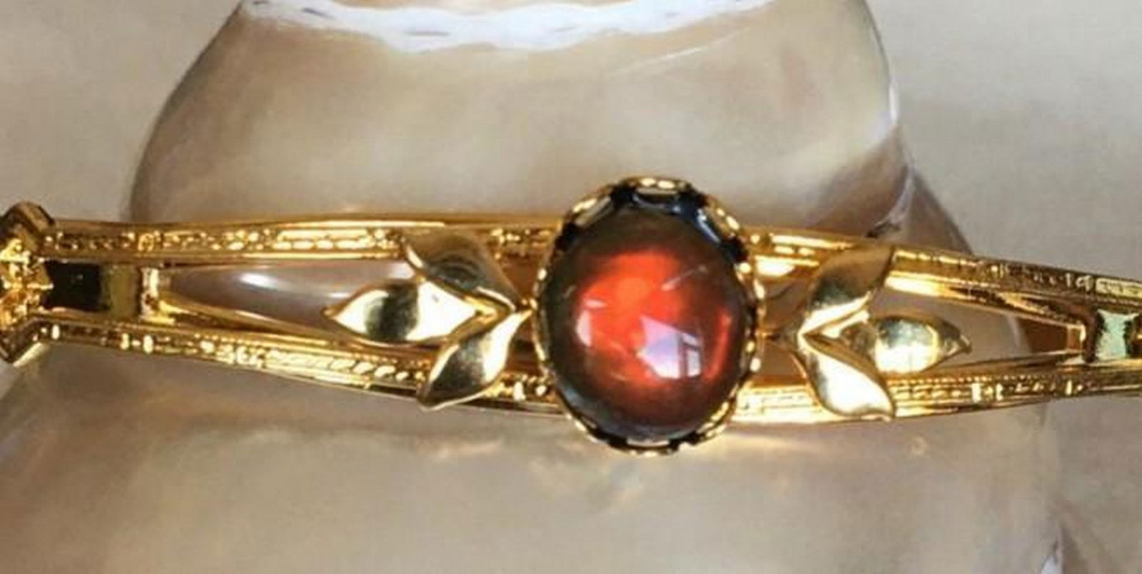 Crimson Shift Ammolite Cuff Bracelet: Crimson Shift Ammolite Cuff Bracelet The Crimson Shift Ammolite Cuff Bracelet features a striking red ammolite gemstone that transforms with light, shifting in colour to reveal a beautiful green. 