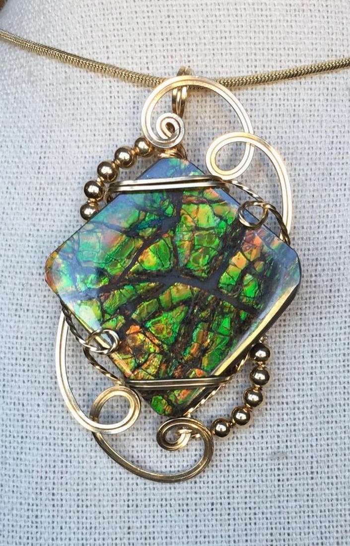 Radiant Stained Glass Ammolite Pendant Necklace: Radiant Stained Glass Ammolite Pendant Necklace This pendant features a freeform ammolite gemstone with no resin coating, displaying vivid orange and green tones with a shimmering effect from natural