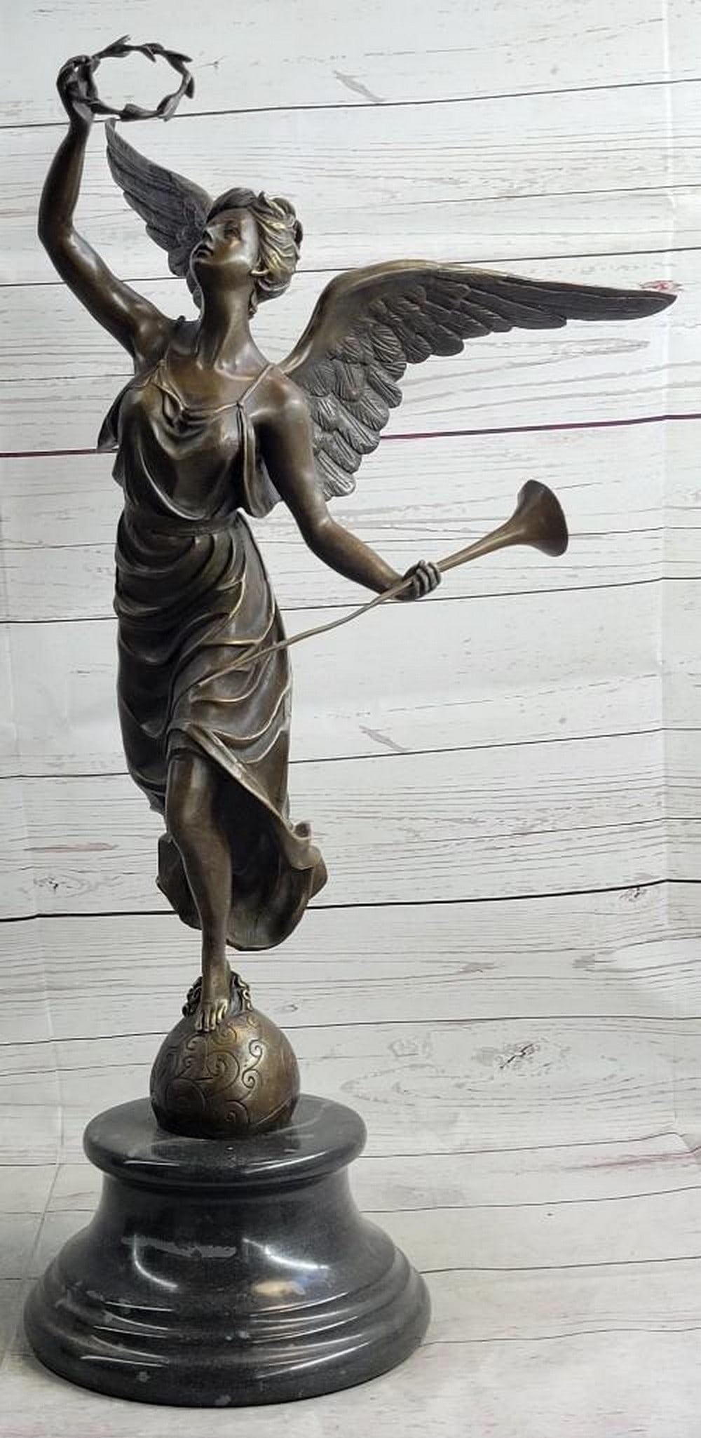 Female Angel Bronze Sculpture: Female Angel Bronze Sculpture This charming angel stand atop a rock about to fly away as she is about to blow on her horn and on her other hand she holds a halo of leaves. her hand is raised high and