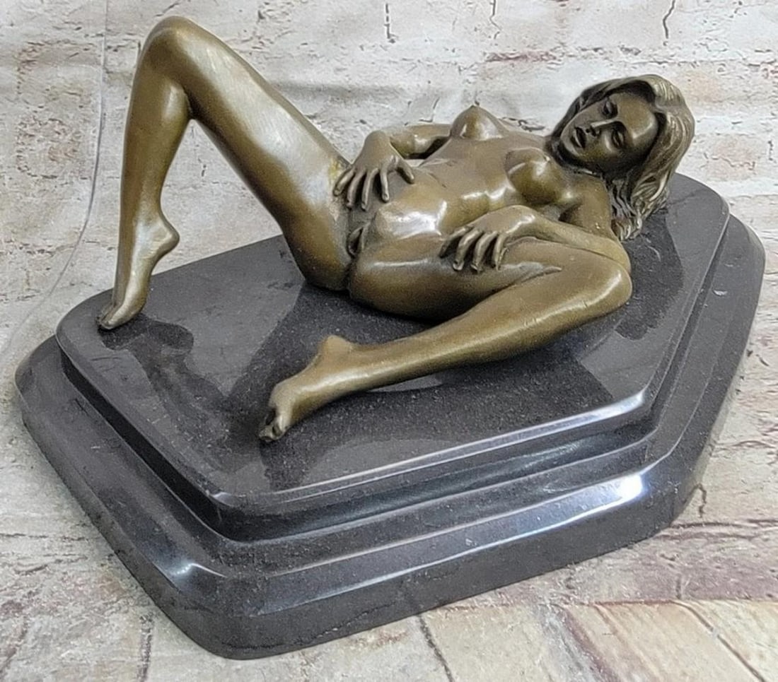 Bronze Nude Woman Sculpture: Bronze Nude Woman Sculpture This is a captivating bronze sculpture that explores themes of self-reflection and intimacy. A serene, nude woman is elegantly positioned on her back, lying upon a polishe